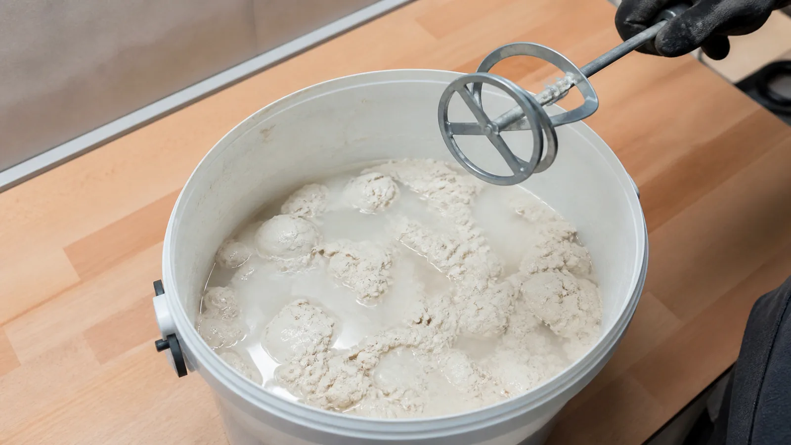 Расслоившийся напольный клей с жидкостью и плотными комками в ведре