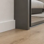 Прямой белый плинтус аккуратно заканчивается у боковины шкафа-купе
